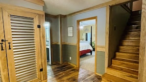 A wooden-floored hallway with a ceiling fan, a door with a window, and a staircase leading to another room. - Rustic cabin just outside of Madison! (Madison)