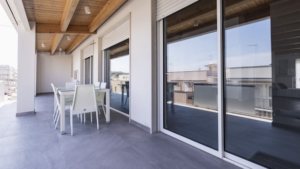 Eine moderne Außenpatio mit Essbereich, großen Schiebeglastüren und Blick auf die Stadtlandschaft.