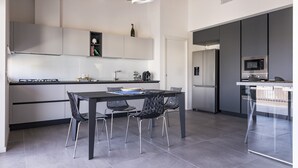 Eine moderne Küche mit Esstisch, Stühlen und einem eingebauten Backofen.
