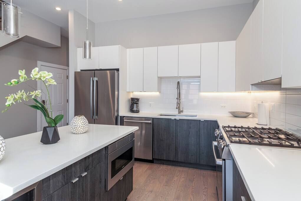 A modern kitchen with white cabinets, stainless steel appliances, and a central island.