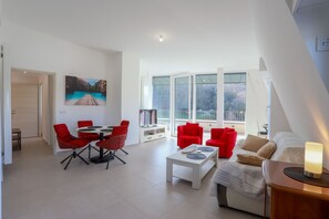 Ein modernes Wohnzimmer mit Essbereich, roten Stühlen, einem weißen Couchtisch und einer Couch mit einer Lampe.