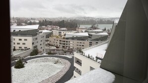 A view from a window overlooking a snowy urban area with modern buildings and a body of water in the distance. - The nest of Lake Annecy (Annecy)