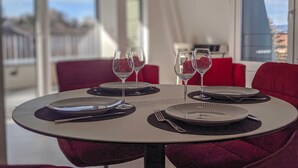 A dining table set with plates, cutlery, and wine glasses, with red chairs around it. - The nest of Lake Annecy (Annecy)