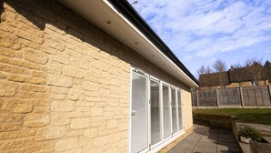A stone building with a large sliding glass door, a brick wall, and a paved patio area.