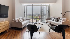 Ein modernes Wohnzimmer mit großem Fenster, zwei Sofas, einem Couchtisch und einem Fernseher.