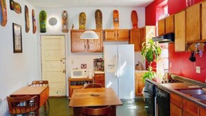 Une cuisine de taille réduite, avec des meubles en bois, un réfrigérateur blanc, une table à manger avec des chaises et un four à micro-ondes.