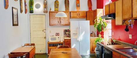 Une cuisine de taille réduite, avec des meubles en bois, un réfrigérateur blanc, une table à manger avec des chaises et un four à micro-ondes.