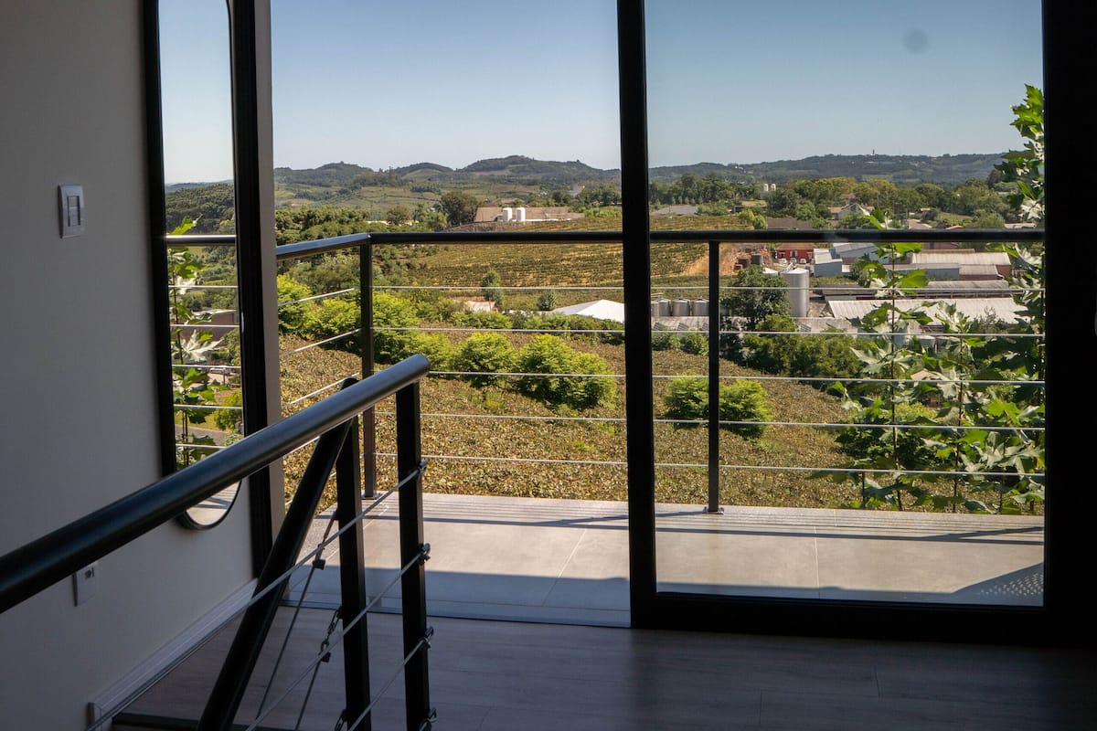 Un balcon offrant une vue sur un vignoble et sur des collines lointaines.