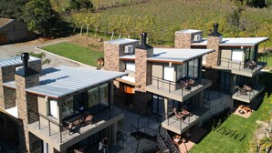Une maison moderne à plusieurs étages, dotée d’un toit plat, de grandes fenêtres et d’espaces extérieurs aménagés pour se détendre.
