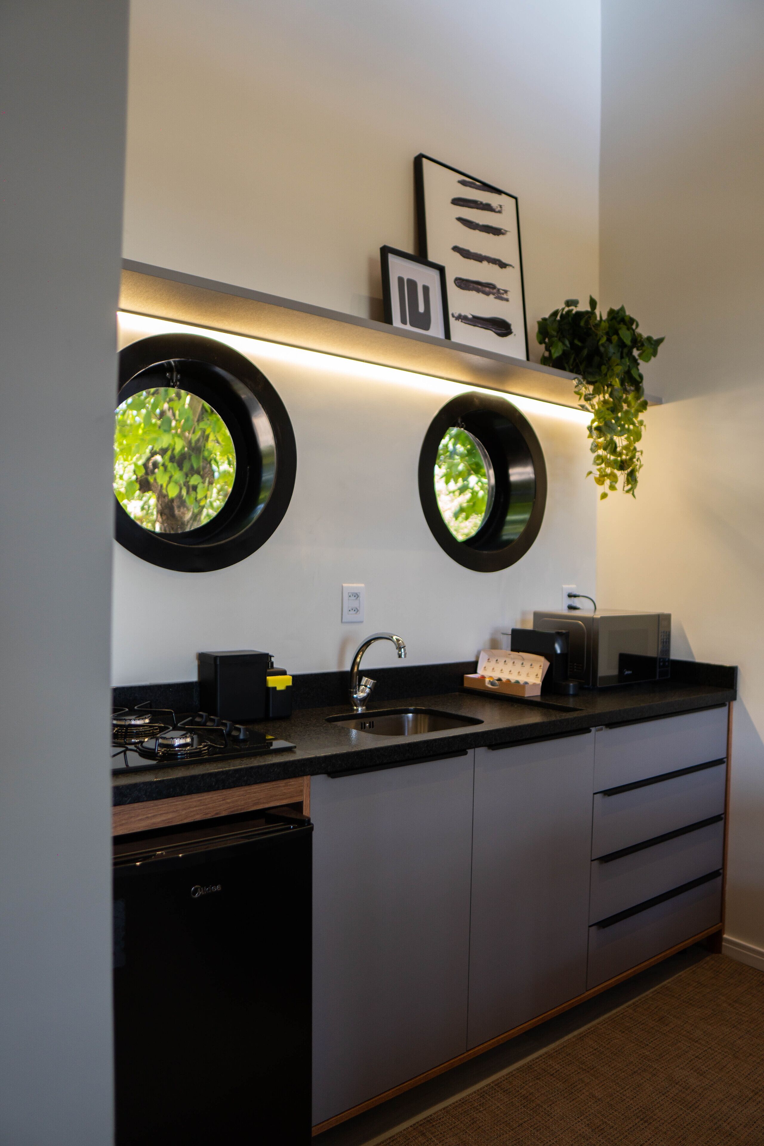 A modern kitchen with a built-in dishwasher, a stove, and a sink. There are two wall-mounted circular mirrors above the counter.