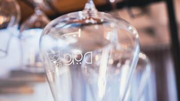A clear glass wine glass with a logo, hanging from a metal rack.
