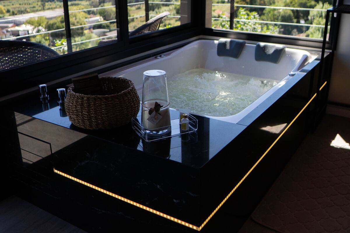 Une salle de bain moderne avec une grande baignoire, un récipient en verre et un panier tressé.