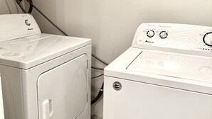 A laundry room with two white washing machines, one with a control panel and the other with a front-loading door. - Spacious 3 Bedroom 2 Bath Condo in Toronto (Toronto)