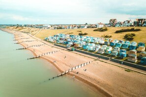 A coastal area with a row of beach huts along the shore and a road leading to them.
