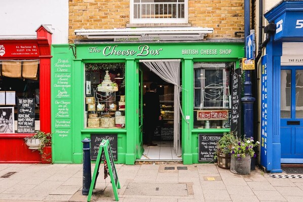 A green storefront with a sign reading "The Cheese Box British Cheese Shop".