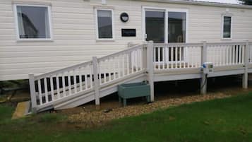 A mobile home with a white exterior, a front deck, and a small porch.