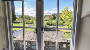 A view through a window with a view of a stone building and a green field.