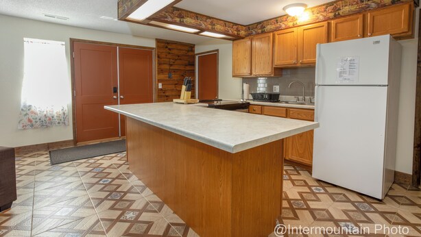Una cucina con armadietti in legno, un frigorifero bianco, un'isola grande e pavimento in piastrelle decorate.