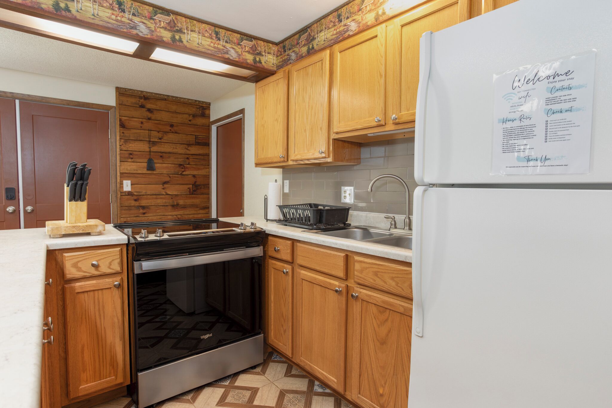 A kitchen with wooden cabinets, a stainless steel stove, and a refrigerator with a welcome sign.