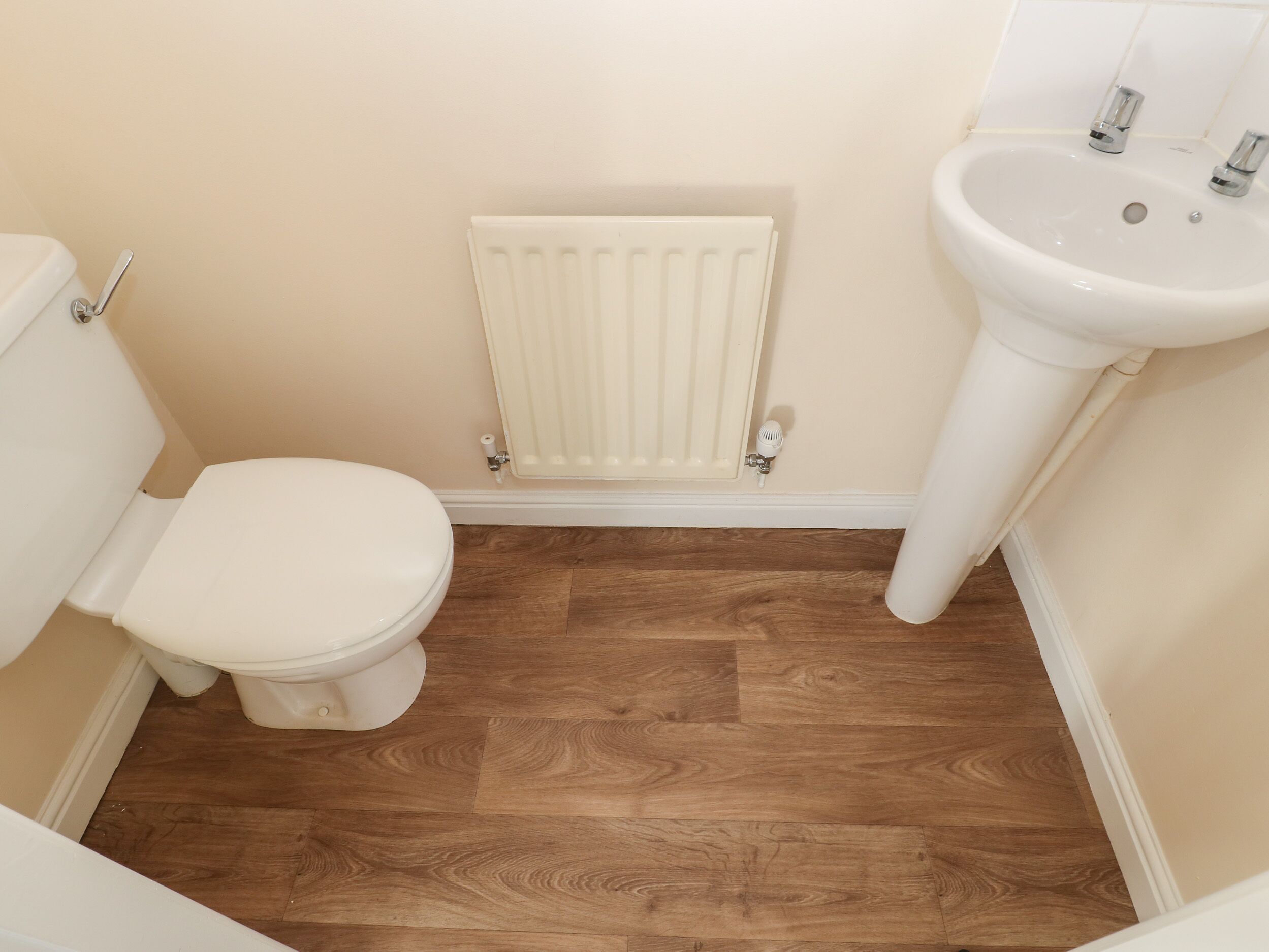 Een kleine badkamer met toilet, een radiator en een wastafel.