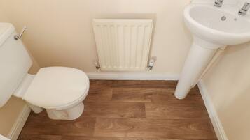 Een kleine badkamer met toilet, een radiator en een wastafel.