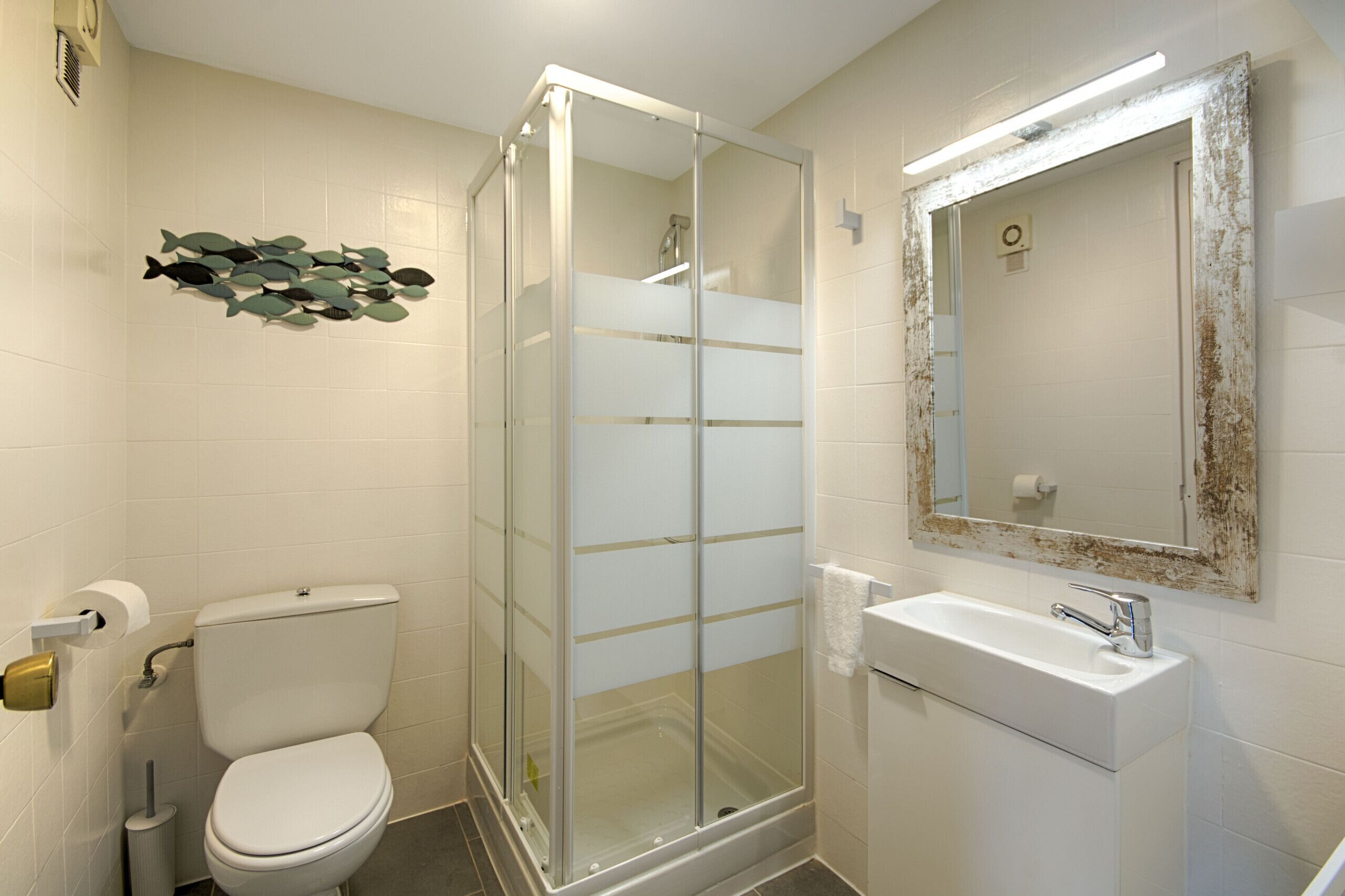 Ein Badezimmer mit einer Duschkabine, einer Toilette und einem Waschbecken mit Spiegel.