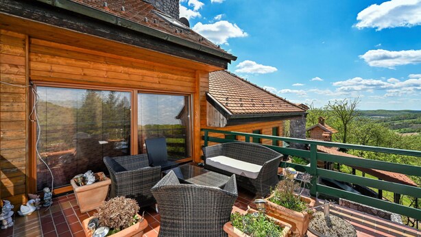 Une cabane en bois dotée d’un balcon, de meubles en osier et de plantes en pot.