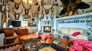 Un salon chaleureux avec une cheminée, un canapé et divers trophées de chasse accrochés aux murs.