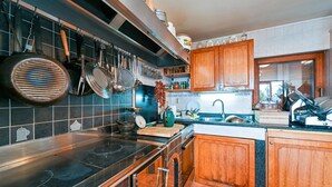 Une cuisine moderne avec un fourneau noir, des armoires en bois et des casseroles suspendues.
