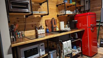 A compact kitchen with a built-in oven, microwave, and red refrigerator.