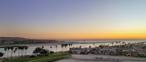 A coastal town with a marina, beachfront properties, and a clear view of the ocean at sunset.