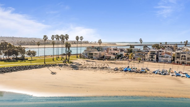 Um hotel costeiro com vários edifícios, uma praia de areia e vista clara para o oceano.
