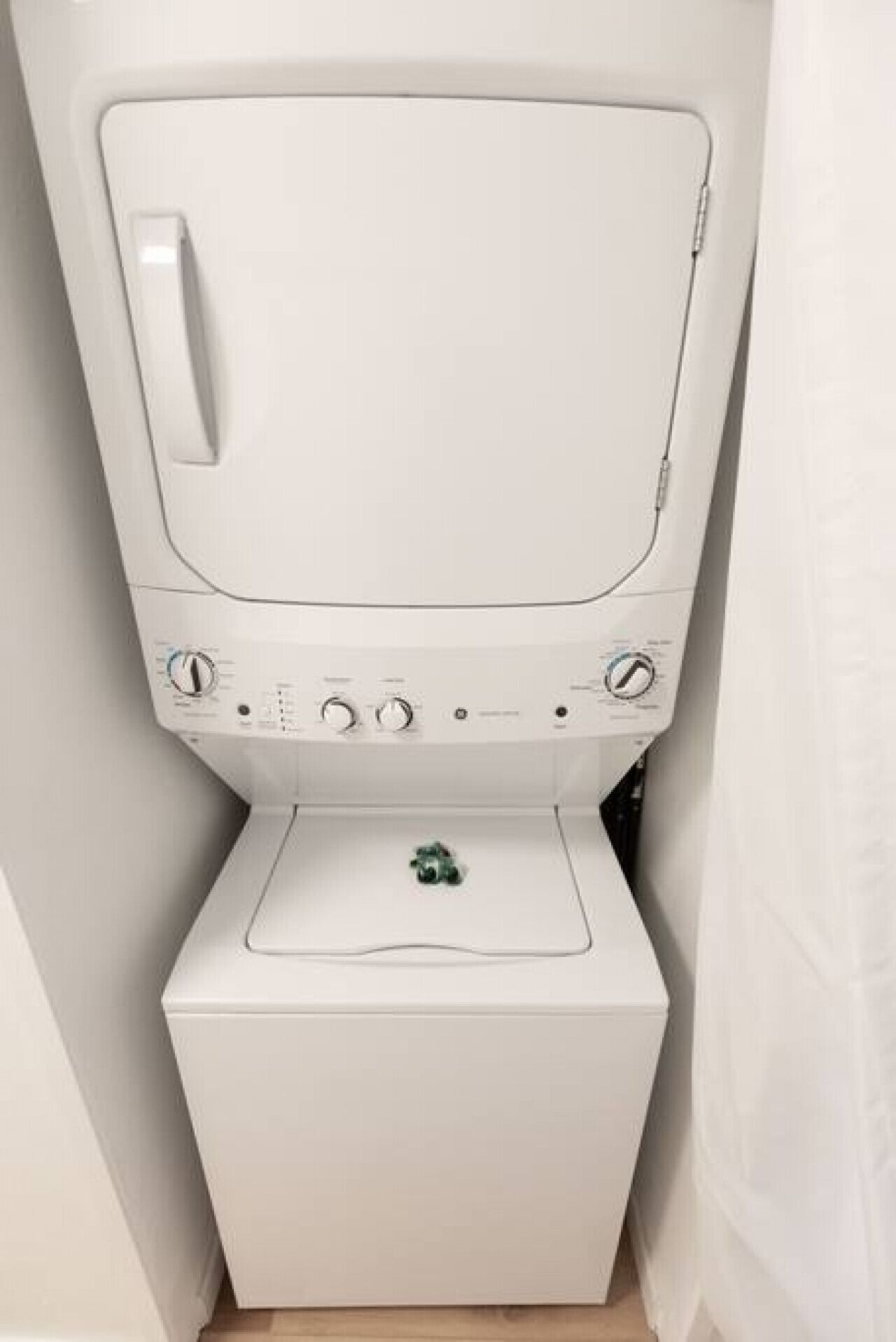 A compact, white, wall-mounted washing machine with a control panel and a small drawer below.