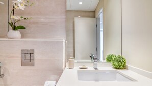 Et moderne badeværelse med en stor vask, et spejl, en orkidé i potte og en lille grøn plante.