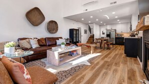 A modern living room with a brown leather sofa, a glass coffee table, and a wooden dining table with chairs. - Remodeled 4BR Chalet | Sleeps 10 | Hot Tub, Pool Access & 5-Min Walk to Lifts (Park City)