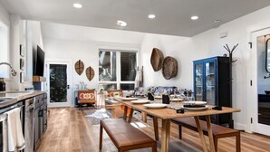 A modern kitchen with wooden flooring, a dining table set for four, and a blue cabinet. - Remodeled 4BR Chalet | Sleeps 10 | Hot Tub, Pool Access & 5-Min Walk to Lifts (Park City)