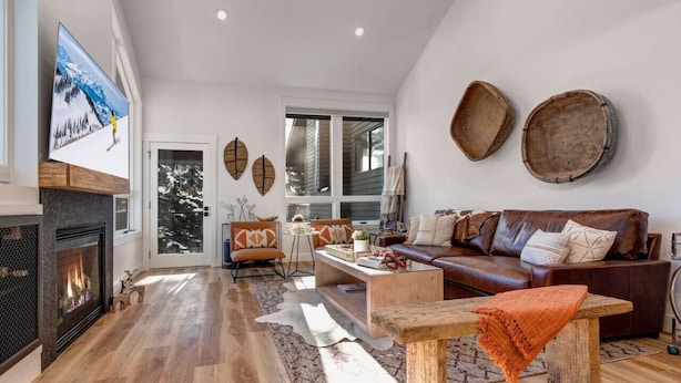 A spacious living room with a fireplace, a large window, and a cozy seating area. - Remodeled 4BR Chalet | Sleeps 10 | Hot Tub, Pool Access & 5-Min Walk to Lifts (Park City)