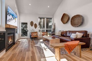 A spacious living room with a fireplace, a large window, and a cozy seating area.