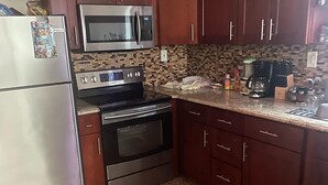 Cozinha com bancadas de granito, eletrodomésticos de aço inoxidável e armários de madeira.