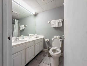 A bathroom with a white sink, mirror, and toilet.