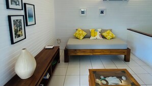 A modern living room with a sofa, coffee table, wooden side table, and framed pictures on the wall.