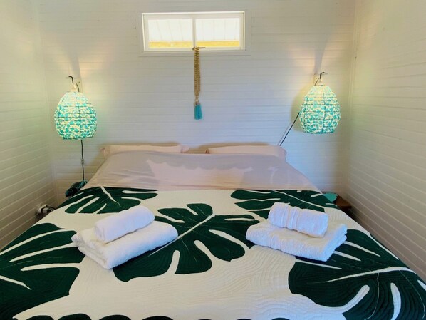 A hotel room with a bed, two wall-mounted lamps, and a window.