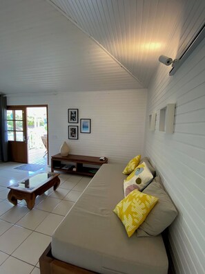 A room with a sofa, a bench, a small table, and a wall-mounted light fixture. - Romantic bungalow with stunning views and swimming pool (TUMARAA)