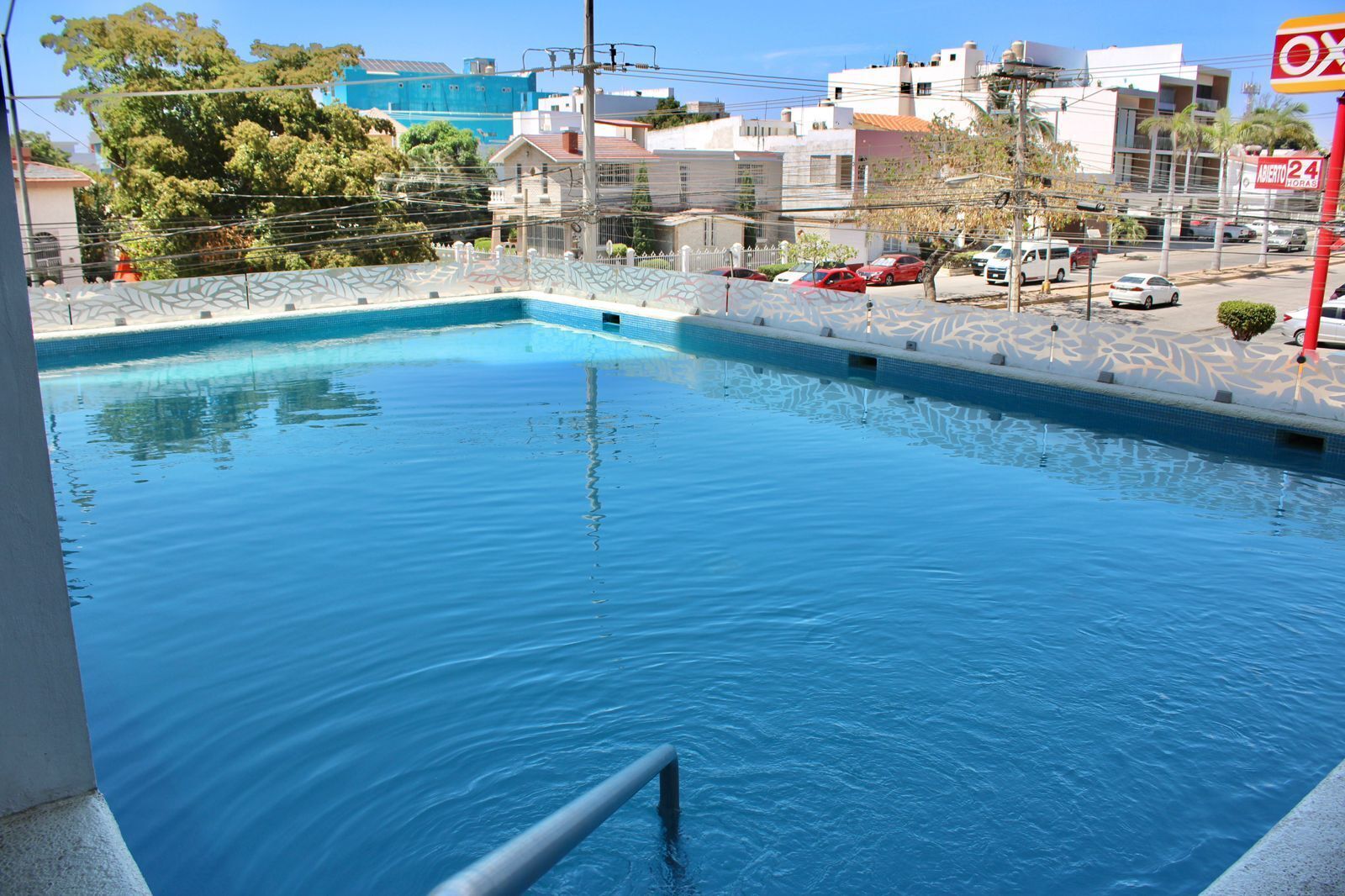 A swimming pool with a clear blue water, surrounded by a white tiled deck.
