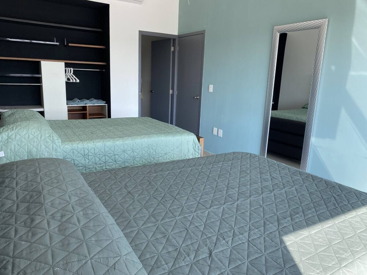 Une chambre avec deux lits, une armoire et un miroir.