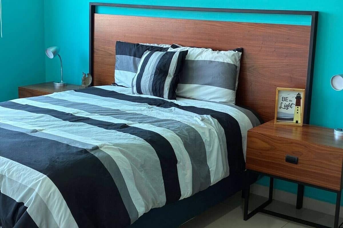 A bed with a striped bedspread, a wooden headboard, and two bedside lamps.