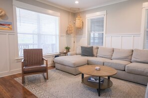 A modern living room with a sectional sofa, a wooden chair, a coffee table, and a small side table with a plant.