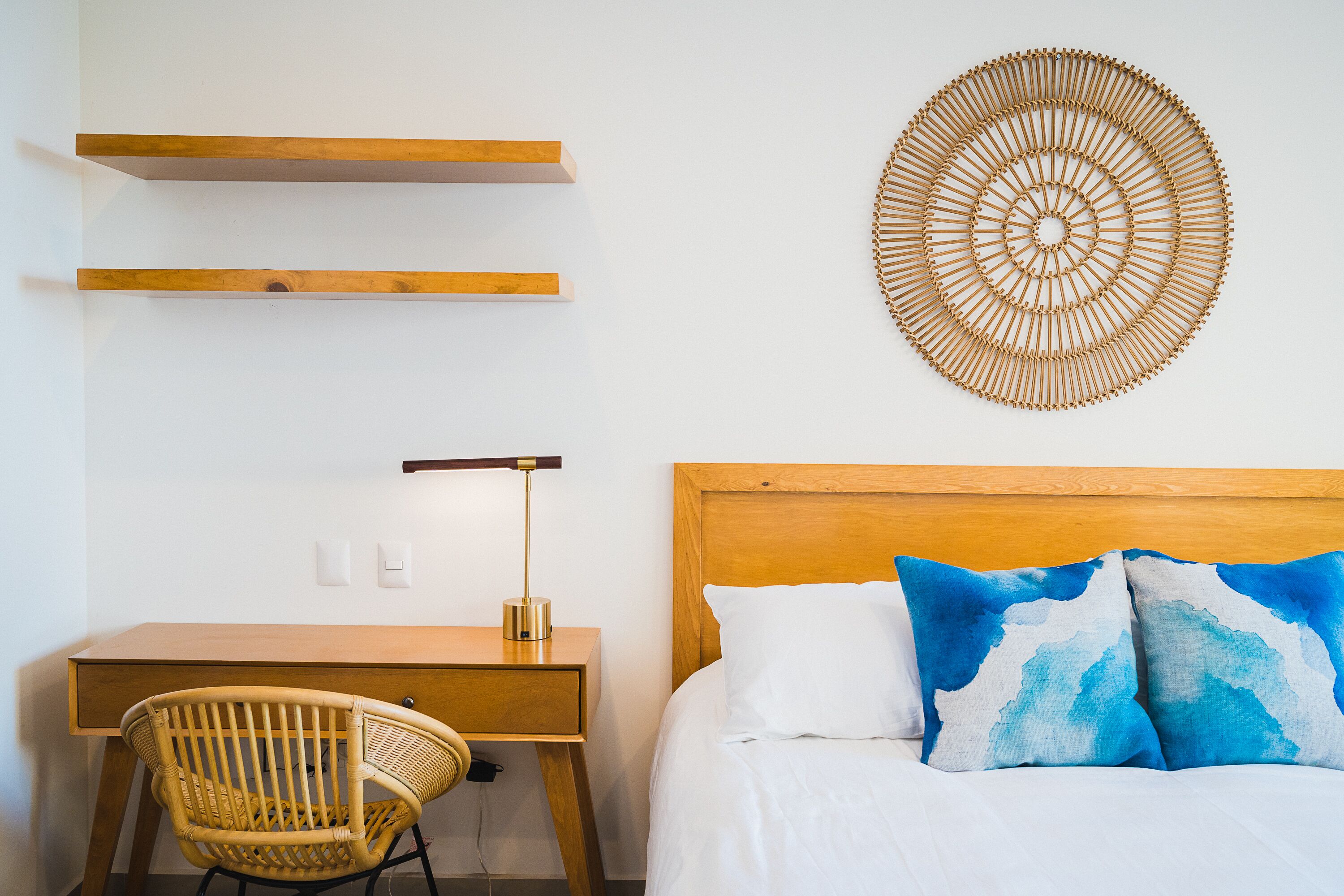 A bedroom with a wooden bed, a desk, a chair, and a wall-mounted circular decorative piece.