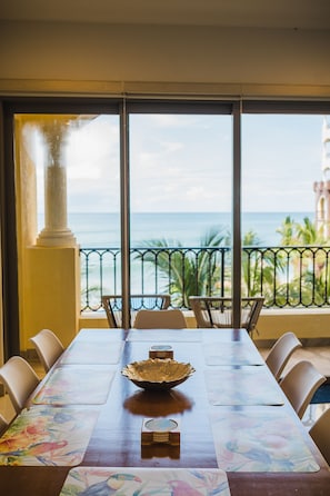 Enjoy meals with a view of the ocean from this dining area featuring a long table and comfortable seating.
