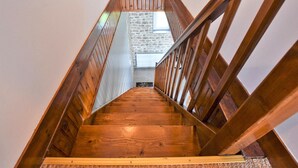 A wooden staircase with a stone wall and a window at the top.